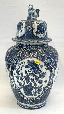 un vase bleu et blanc surmonté d'un chat