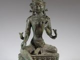 une statue en bronze représentant une femme assise sur un lotus