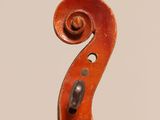 a close up of a violin neck with a fiddle in the background