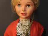 a close up of a doll wearing a red coat