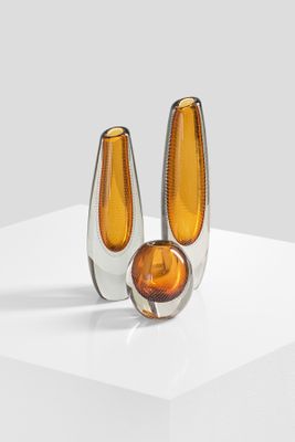 pair of orange glass vases sitting on top of a white surface