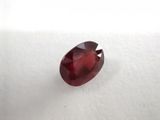 a close up of a red garnet stone on a white surface