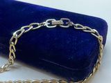 a silver chain bracelet on a blue velvet case