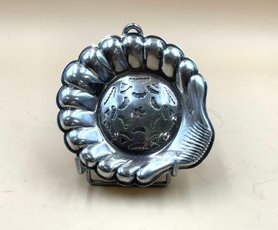 assiette en argent sur laquelle figure une main tenant un globe terrestre