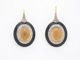 une photo d'une paire de boucles d'oreilles noires et dorées ornées de diamants