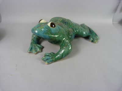 une figurine de grenouille verte posée sur une surface blanche