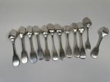 six spoons and a fork are arranged in a row on a table
