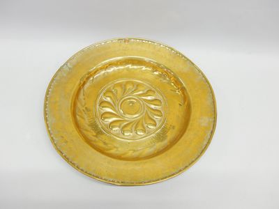 une plaque en or ornée d'un motif décoratif sur un fond blanc