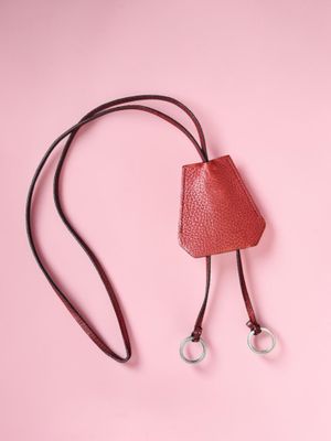 a red leather bag with two metal rings on a pink background
