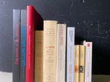 Plusieurs livres sont alignés sur une étagère devant un mur noir