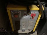 une machine jaune et noire posée par terre à côté d'un sac noir