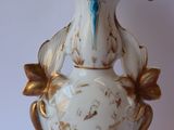 a white and gold vase with a blue bow on it