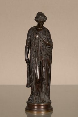 une statue antique en bronze représentant une femme tenant un panier