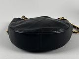a black purse with a chain around it sitting on a white surface