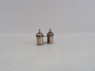 une paire de salières et poivrières en argent posées sur une surface blanche