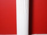 a white column with a red wall in the background