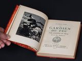 quelqu'un tient un livre ouvert sur lequel figure la photo d'un homme portant un chapeau