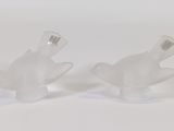 une paire de figurines de poissons en verre transparent posées sur un fond blanc