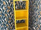 a yellow shelf in the corner of a room