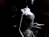 photographie en noir et blanc d'une femme en robe, debout devant un miroir