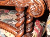 a close up of a wooden chair with a colorful upholstered seat