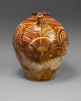 a brown vase with designs on it on a gray surface