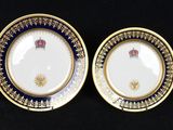 two plates with gold and blue designs on them on a black surface