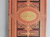 an old book with a gold and red cover sitting on a table