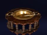 une assiette en or posée sur un support en bois, avec une cuillère à l'intérieur