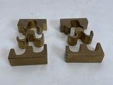 two pieces of brass metal are sitting on a white surface