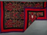 a close up of a red and black scarf on a table