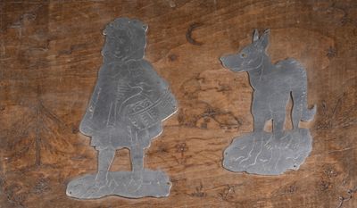 deux figurines en métal représentant un garçon et un chien, posées sur une table en bois