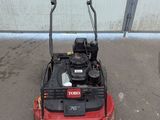 a red lawn mower parked in front of a garage