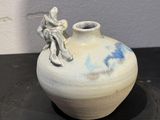 a white vase with a figurine sitting on top of it