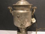 a silver urn with a bird on it on a table
