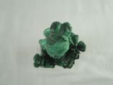 a small figurine of a frog sitting on a white surface