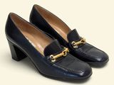 un gros plan sur une paire de chaussures noires ornées d'une chaîne dorée