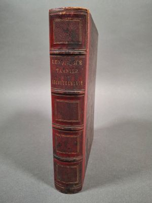 un vieux livre rouge posé sur une table blanche