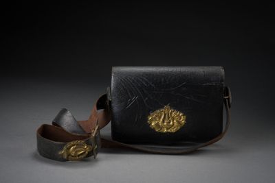 black leather purse with a gold lion on the front and a leather strap