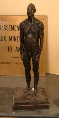 a bronze statue of a man standing next to a sign