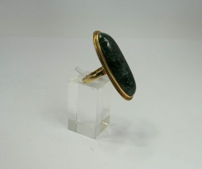 an image of a ring with a green stone on a clear stand