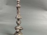 an antique silver plated candle holder on a grey background