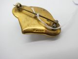 une broche en or à laquelle est attaché un fil