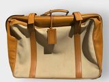 beige and tan canvas briefcase with leather handles on a white surface
