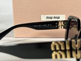 black sunglasses with gold details and a pink box on a white surface