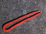 a close up of a red beaded necklace on a black surface