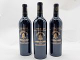 trois bouteilles de vin rouge posées l'une à côté de l'autre sur une surface blanche