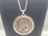 a close up of a necklace with a coin on a mannequin
