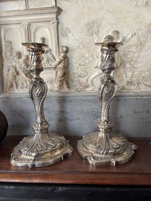 two silver candles sitting on a table next to a vase