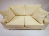 cream colored couch with two pillows on top of it on a white background